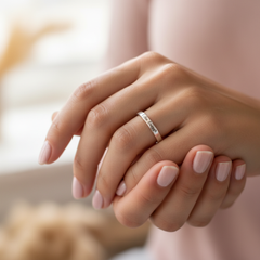 I Am Enough engraved silver ring resting on soft hands with warm pink and gold background